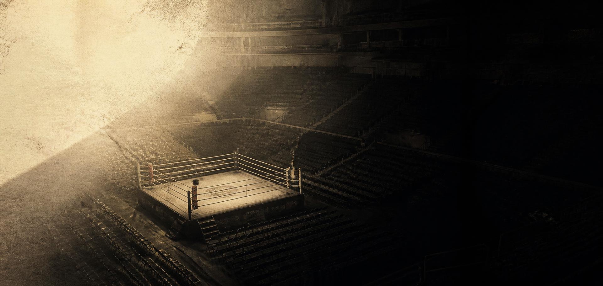 An empty boxing ring in a darkened arena
